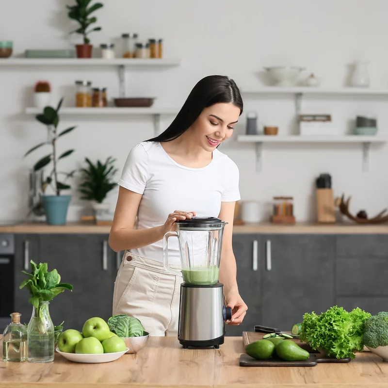 Frau erstellt einen Smoothie mit grünem Gemüse